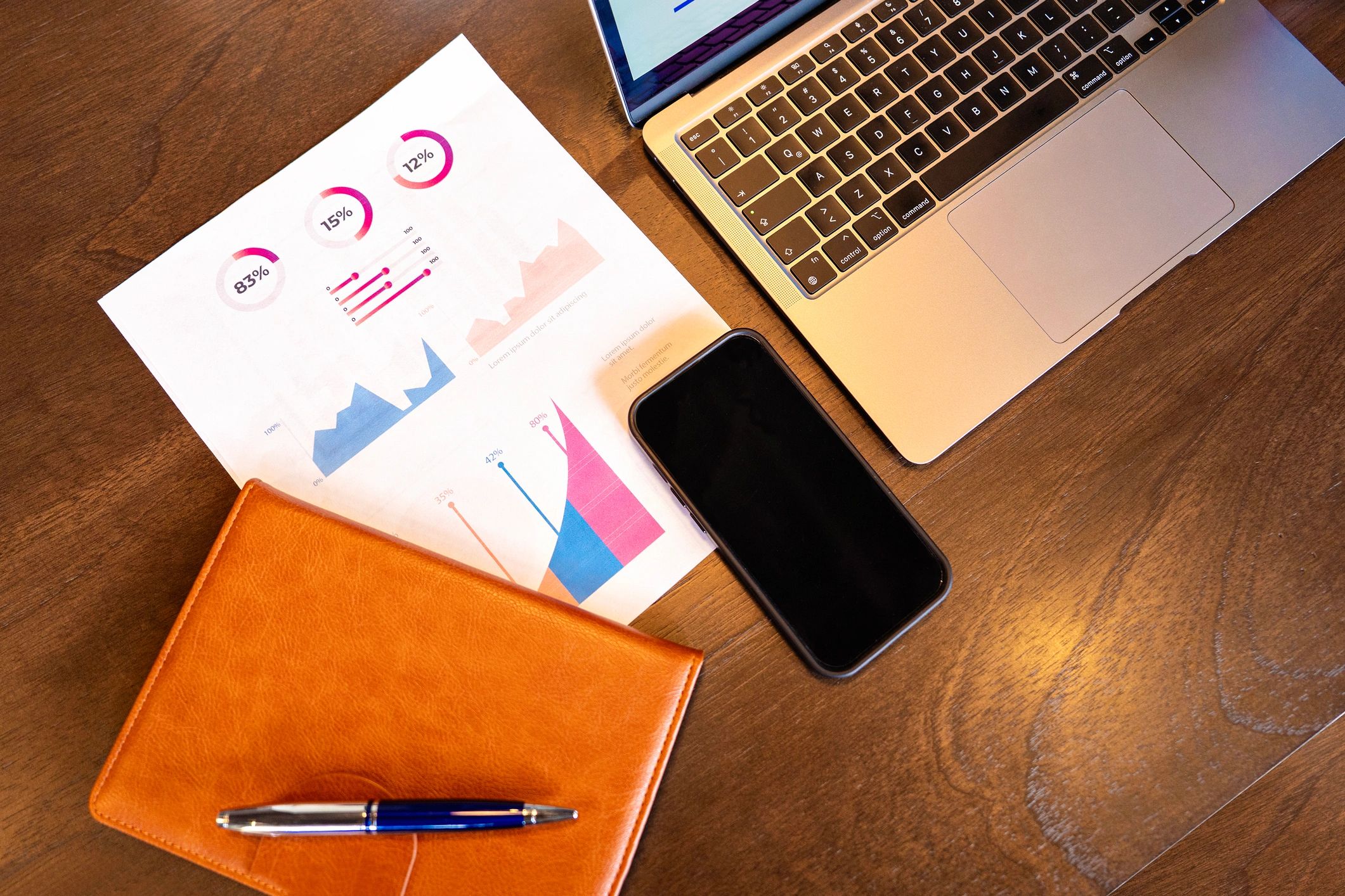 Planner and business reports next to a laptop